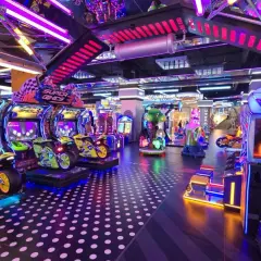 Kolorowy park rozrywki w Łodzi z maszynami do gier, w tym motocyklami i wyścigami.