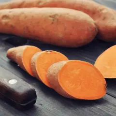 Całe i pokrojone bataty na drewnianym blacie. Dowiedz się, ile gotować bataty, by były idealne.