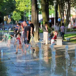 Dzieci bawią się w fontannie, a dorośli odpoczywają w cieniu drzew. To jedne z wielu bielsko biała atrakcje w upalny dzień.